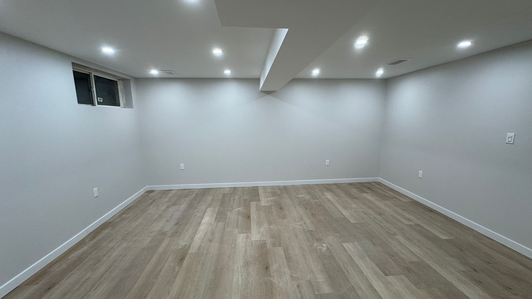 Finished basement with stepped soffit, pot lights and oak vinyl flooring