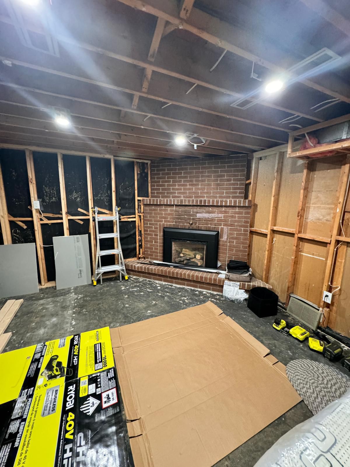 The same basement before — open studs and bare brick fireplace