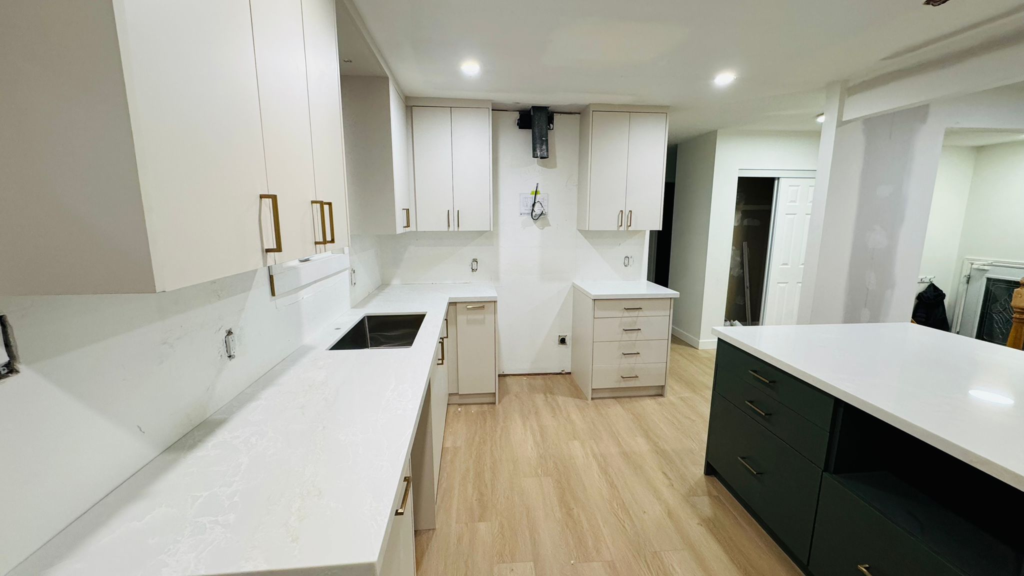 White shaker kitchen cabinets with brass pulls and quartz counter detail